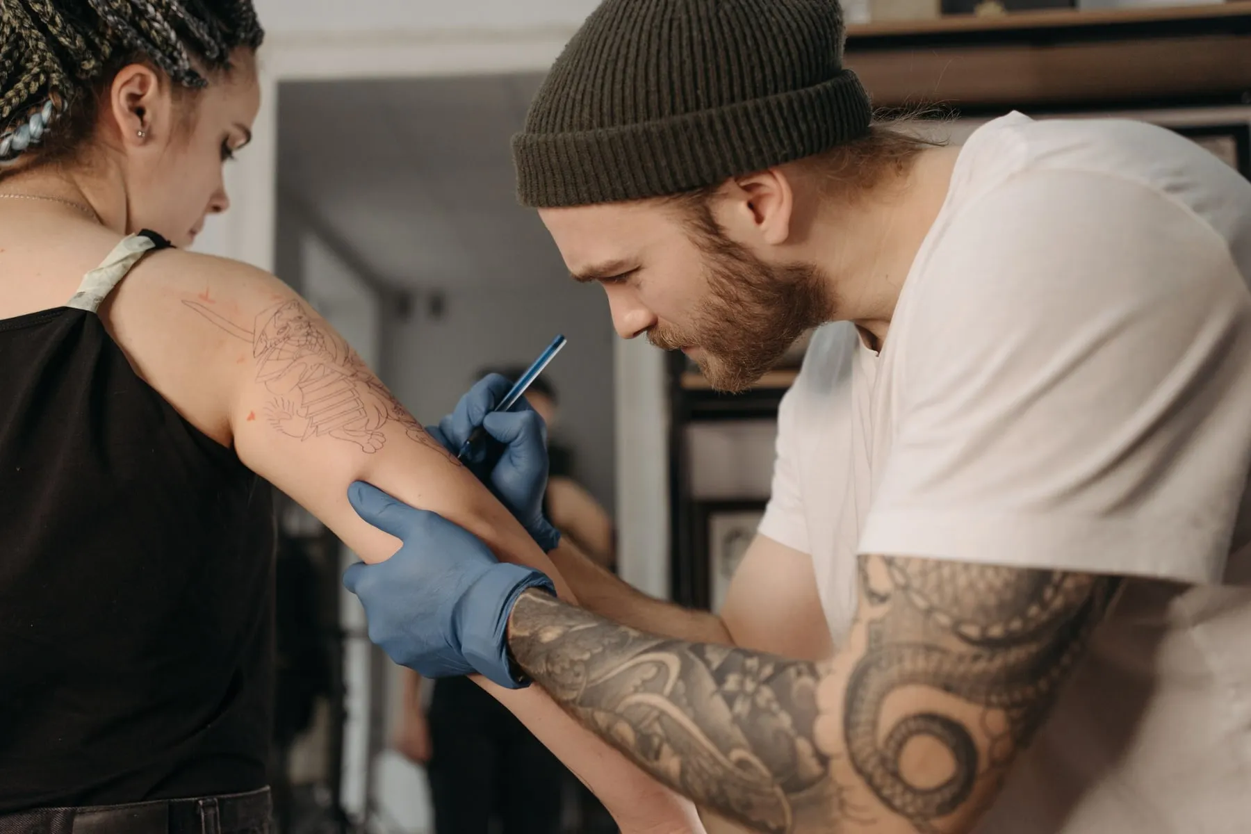 Ana drawing a stencil directly onto a client’s forearm before the session starts.