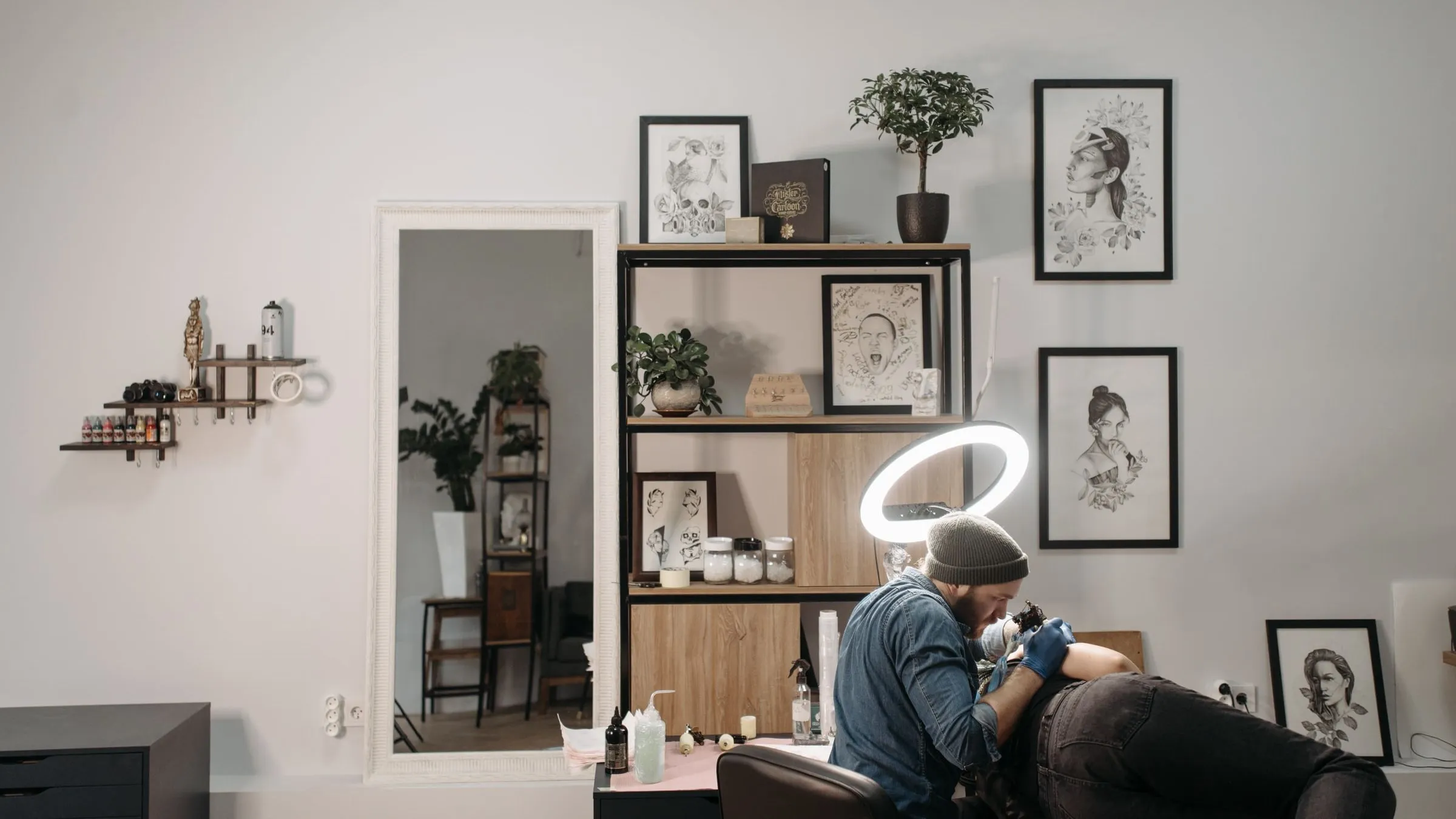The studio: one bright room with framed drawings along the wall, a shelf of reference prints and the chair set up under a lamp.