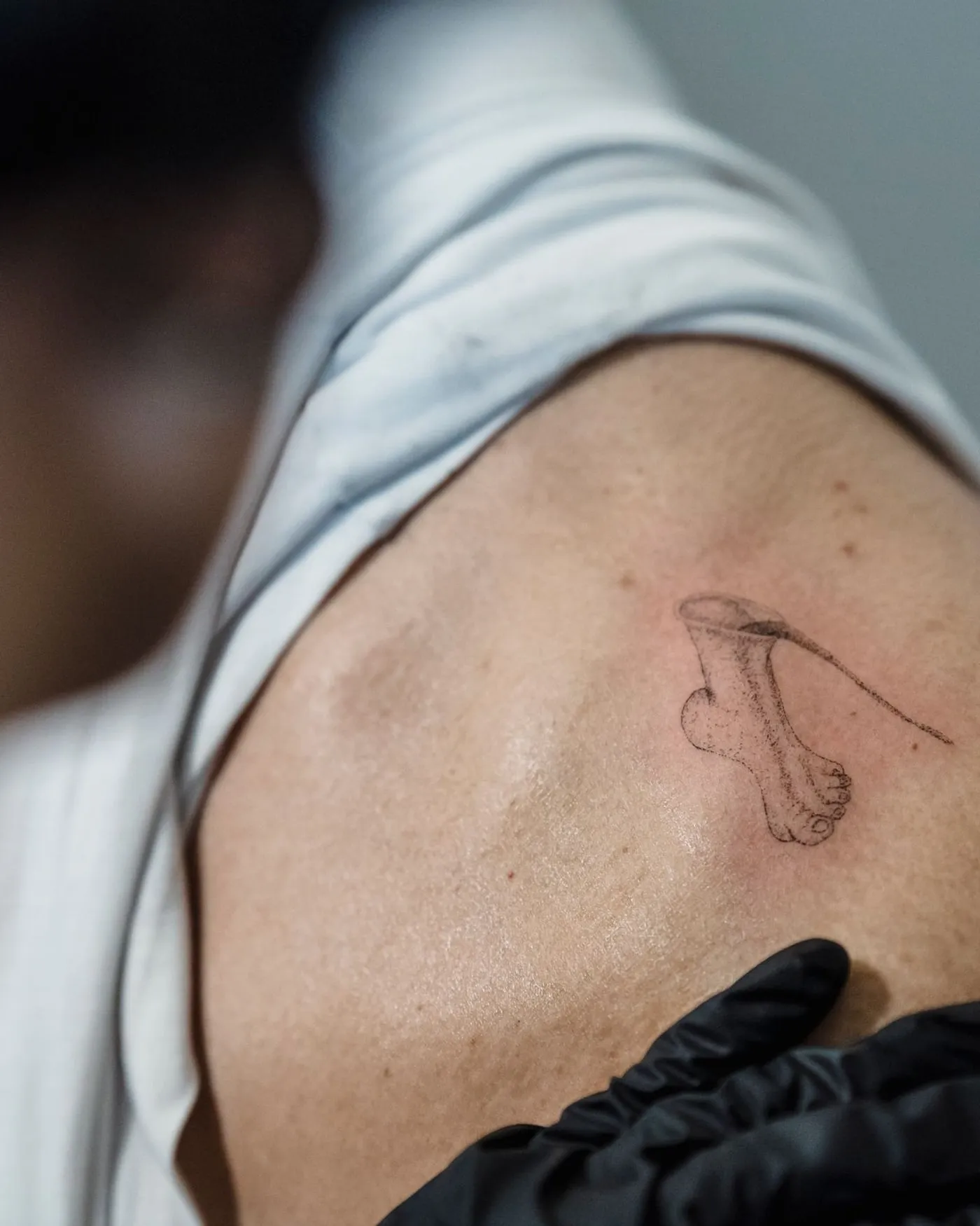 A fine-line cherry and stem across the top of the shoulder, freshly finished.