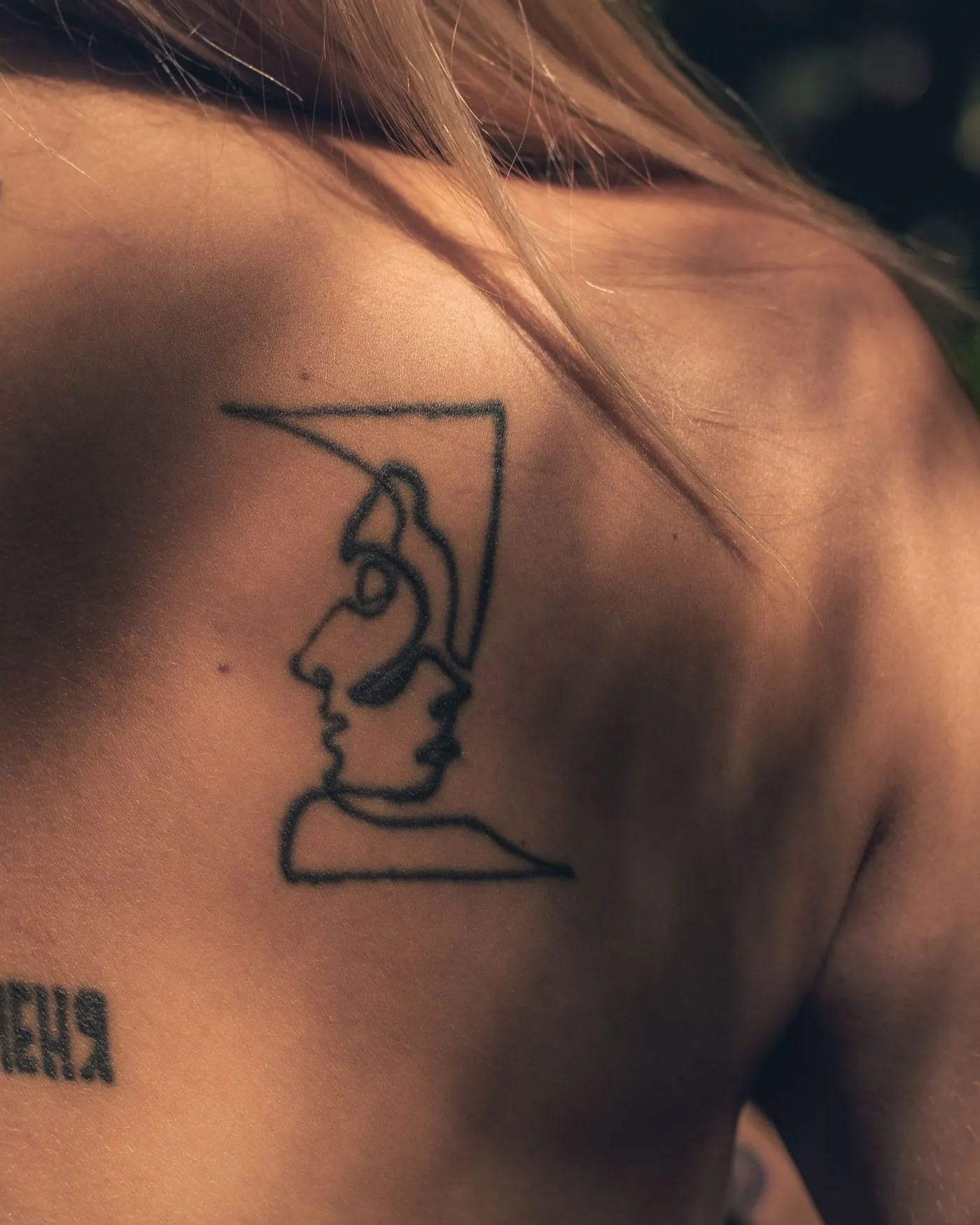 A continuous single-line drawing of a figure across the upper back.