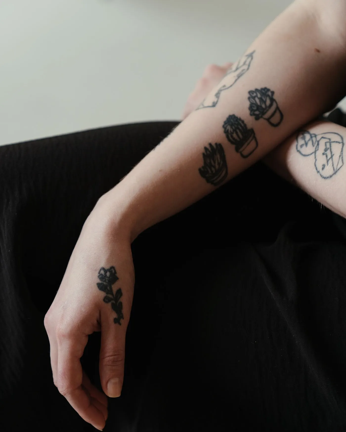 A collection of small fine-line pieces on the upper arm, photographed against a dark background.